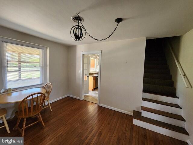 dining room featuring a notable chandelier, dark wood-style flooring, stairway, and baseboards