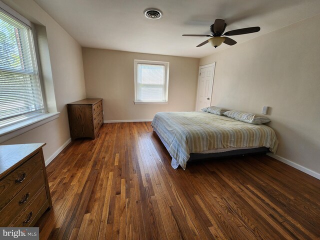 bedroom with dark wood-style floors, a ceiling fan, visible vents, and baseboards