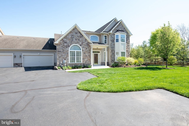 view of front of home featuring an attached garage, driveway, a front lawn, and stone siding