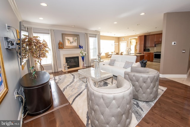 living area featuring recessed lighting, baseboards, ornamental molding, and wood finished floors