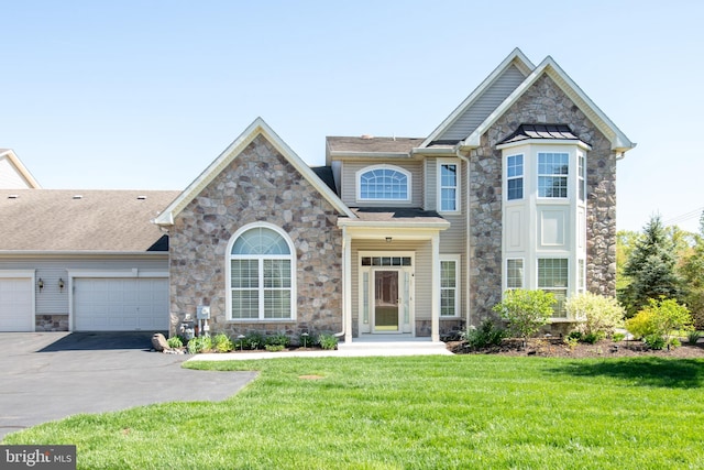 view of front of home with a garage, driveway, a front yard, and stone siding