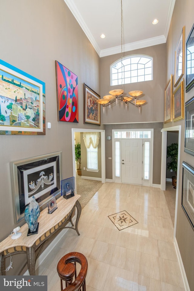 foyer featuring baseboards, ornamental molding, plenty of natural light, and a towering ceiling