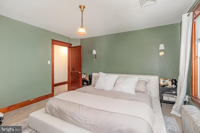 bedroom with radiator heating unit, baseboards, visible vents, and light colored carpet