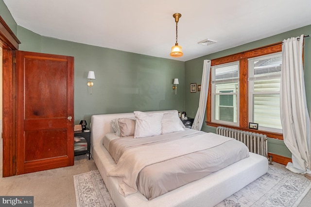 bedroom featuring radiator heating unit, light colored carpet, and visible vents