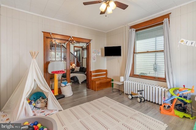 playroom with ornamental molding, radiator, ceiling fan, and wood finished floors