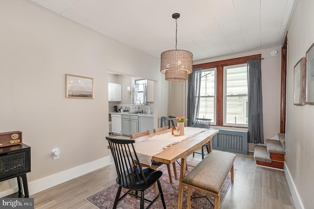 dining space featuring baseboards, a notable chandelier, light wood-style flooring, and stairway