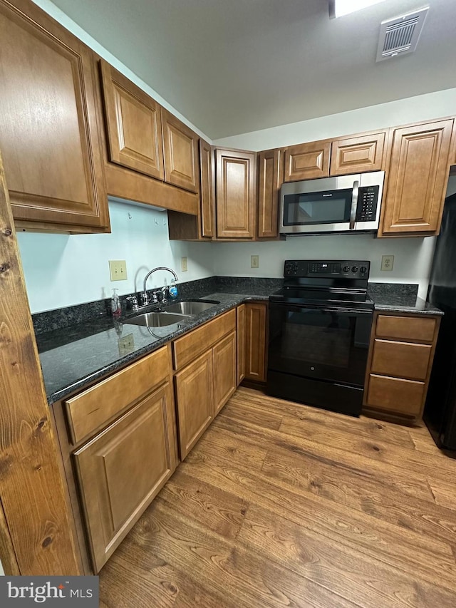 1 Warthens Way Unit H, Emmitsburg, MD 21727 - kitchen featuring black appliances, a sink, light wood-style floors, dark stone countertops, and brown cabinets