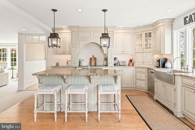 kitchen featuring light stone counters, plenty of natural light, and cream cabinets
