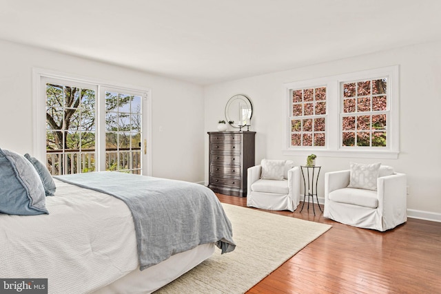 bedroom with baseboards, access to exterior, and wood finished floors