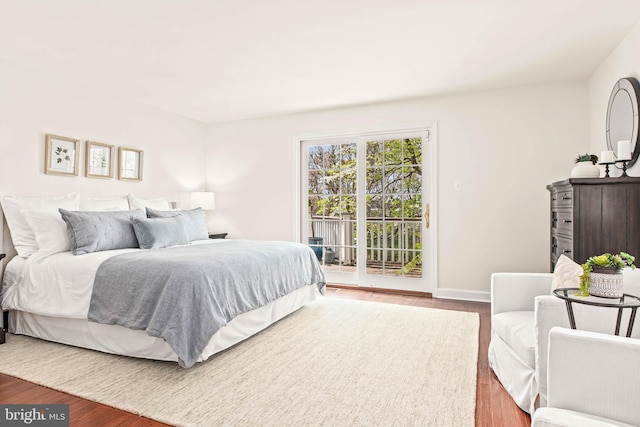 bedroom with baseboards, access to outside, and wood finished floors