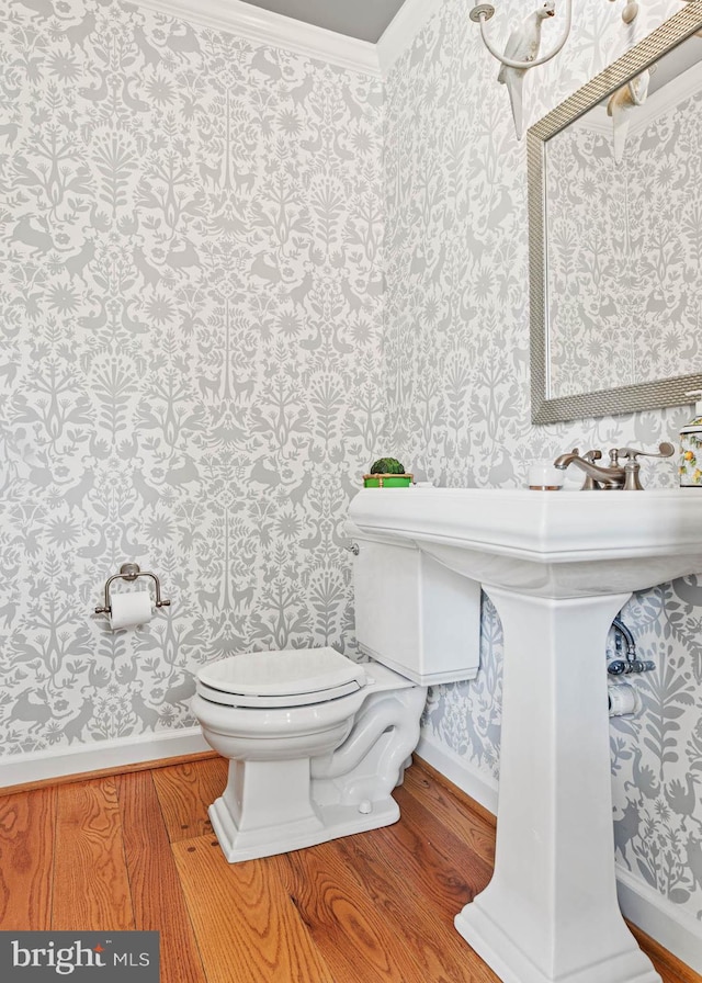 bathroom with ornamental molding, wood finished floors, toilet, baseboards, and wallpapered walls