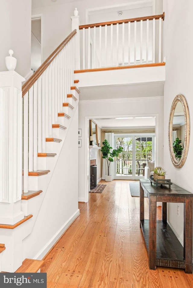 entryway featuring baseboards, a high ceiling, and light wood-style flooring