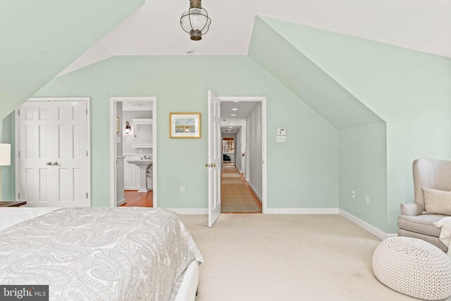 bedroom featuring baseboards, connected bathroom, carpet, and vaulted ceiling