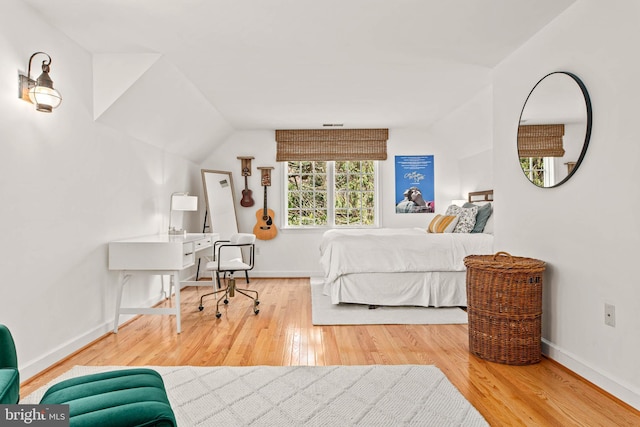 bedroom with baseboards, vaulted ceiling, and wood finished floors