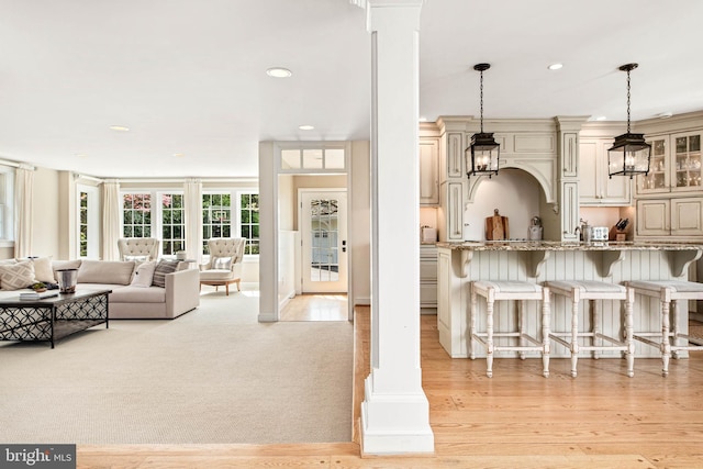 living room featuring recessed lighting, ornate columns, and light wood-style flooring
