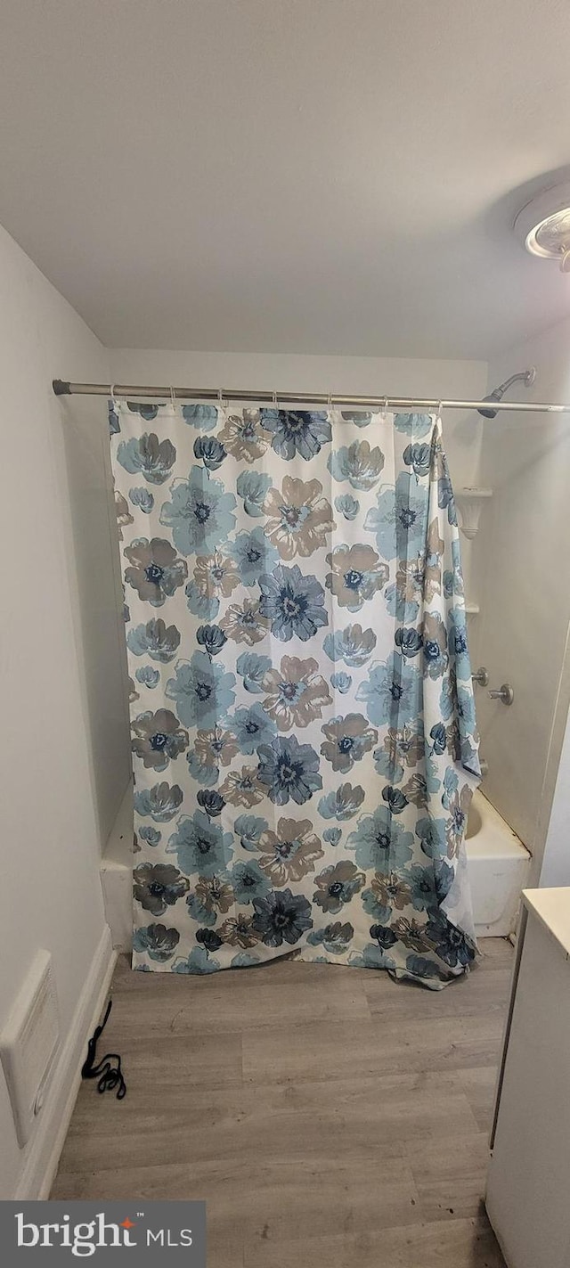 full bath with shower / bath combo with shower curtain, visible vents, and wood finished floors