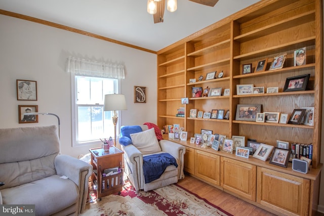 sitting room featuring a ceiling fan, ornamental molding, built in features, and light wood-type flooring