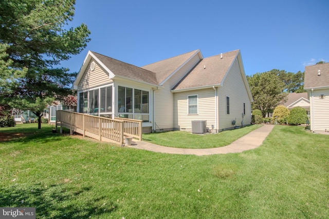 rear view of house featuring a lawn, central AC, and a sunroom