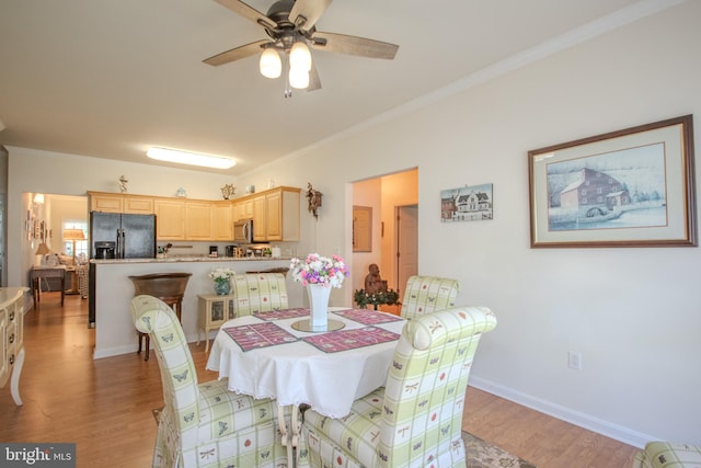 dining area featuring a ceiling fan, baseboards, ornamental molding, and light wood-style floors