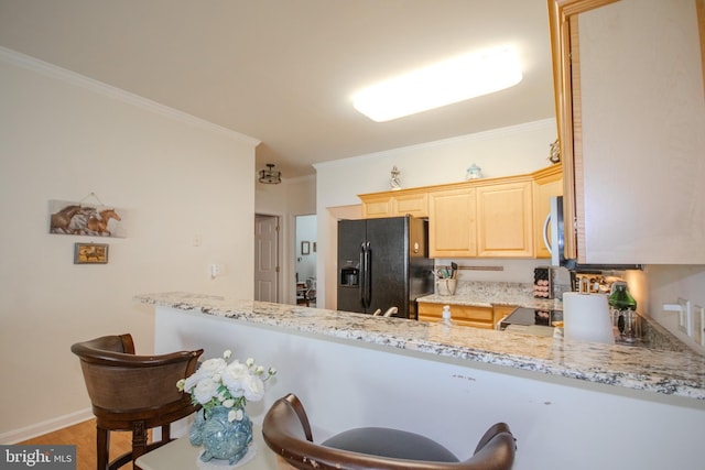kitchen with crown molding, light brown cabinetry, light stone countertops, stainless steel microwave, and black refrigerator with ice dispenser