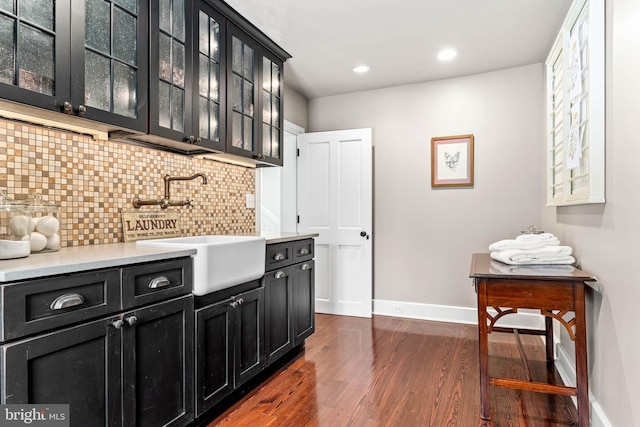 bar area featuring a sink, dark wood-style flooring, decorative backsplash, baseboards, and recessed lighting