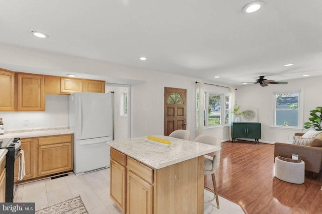 kitchen with stainless steel range, freestanding refrigerator, recessed lighting, open floor plan, and a kitchen bar
