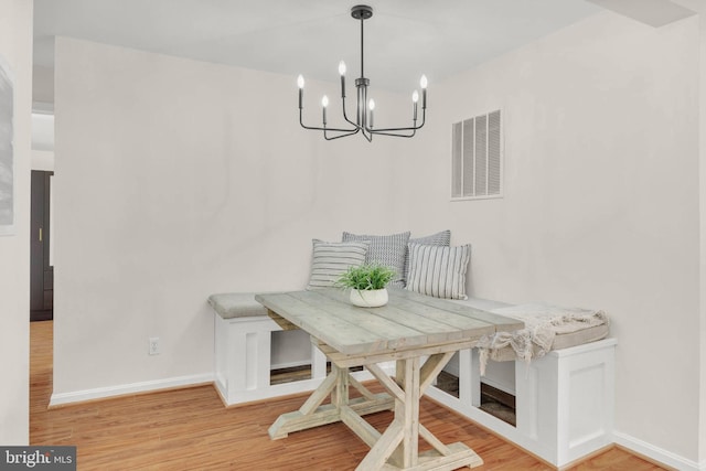 dining area with a chandelier, baseboards, visible vents, and wood finished floors