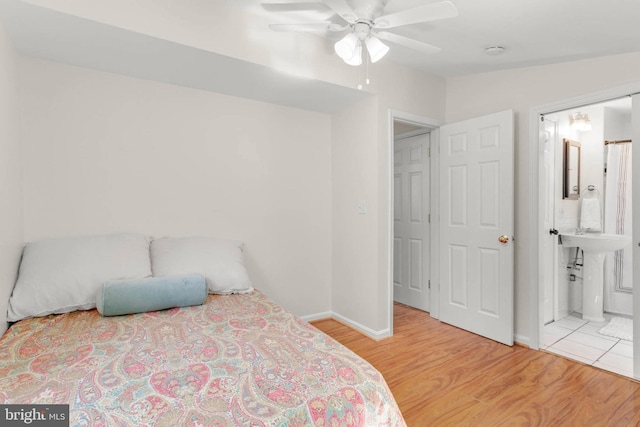bedroom featuring ceiling fan, baseboards, ensuite bathroom, and wood finished floors