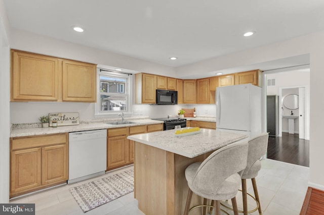 kitchen with a kitchen island, a breakfast bar, recessed lighting, a sink, and black appliances
