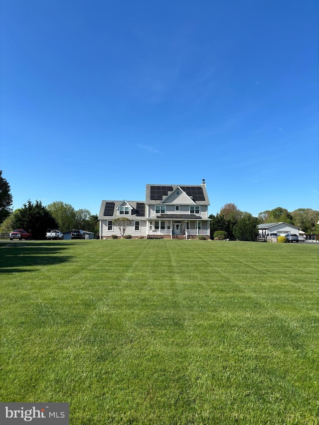 back of property featuring a lawn, solar panels, and a chimney