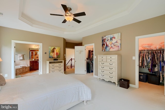 bedroom with a walk in closet, a tray ceiling, a closet, and ornamental molding