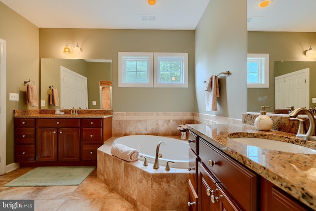 bathroom featuring a bath and two vanities