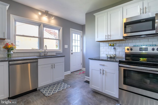 kitchen with appliances with stainless steel finishes, white cabinetry, decorative backsplash, and a sink
