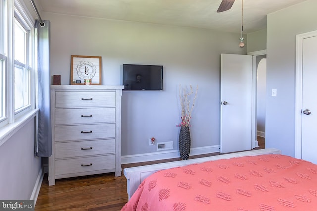 bedroom featuring dark wood-style floors, a ceiling fan, visible vents, and baseboards