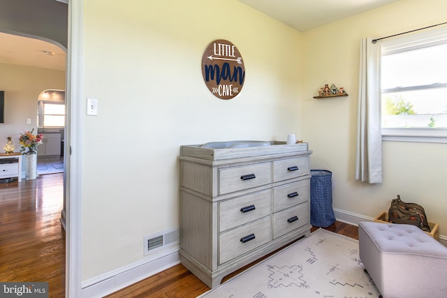 details featuring baseboards, visible vents, arched walkways, and wood finished floors