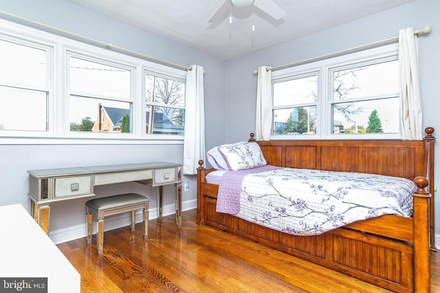 bedroom featuring baseboards, wood finished floors, and multiple windows