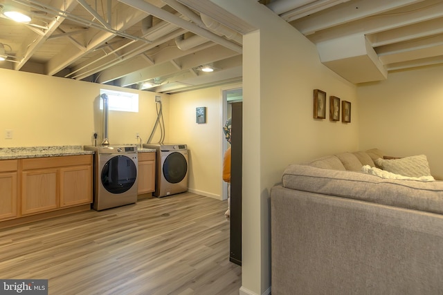 washroom with light wood-type flooring, separate washer and dryer, and baseboards