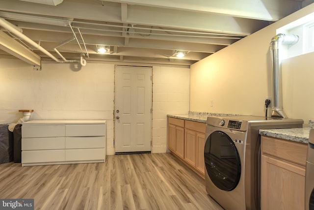 clothes washing area featuring light wood-type flooring, cabinet space, concrete block wall, and washer / clothes dryer