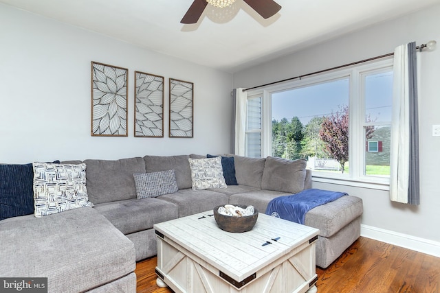 living area with baseboards, wood finished floors, and ceiling fan