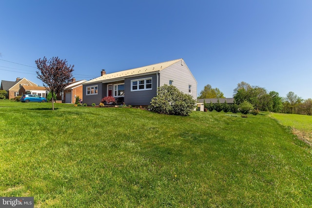 rear view of property featuring a chimney, a yard, and a garage