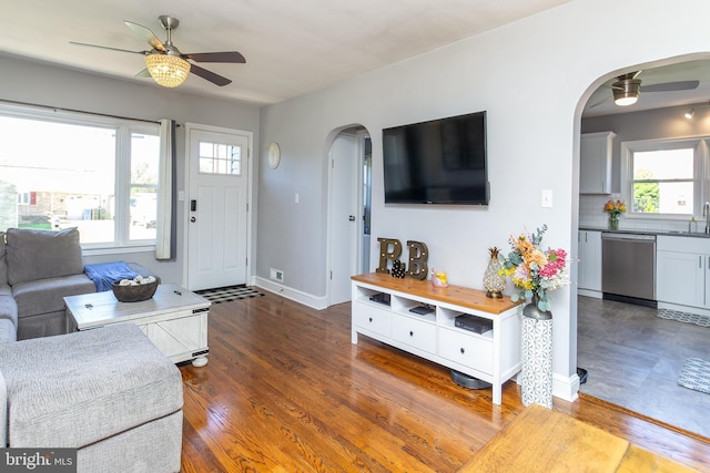 living area with arched walkways, ceiling fan, and a wealth of natural light