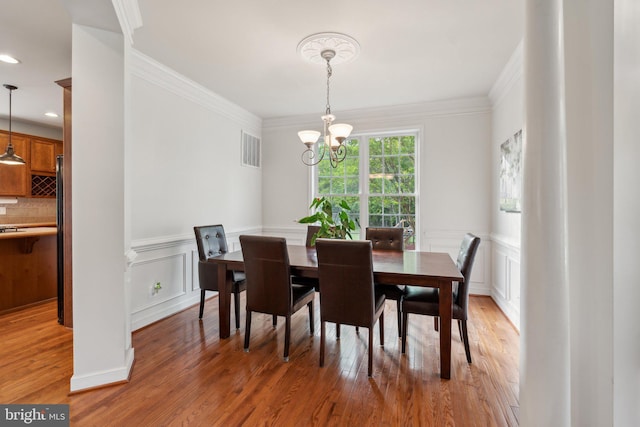 6 Crawford Ln, Stafford, VA 22556 - dining room featuring visible vents, crown molding, an inviting chandelier, a decorative wall, and light wood-style flooring