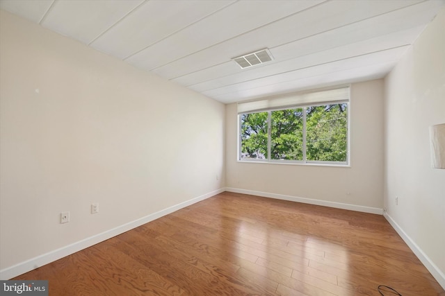 unfurnished room with baseboards, wood finished floors, and visible vents