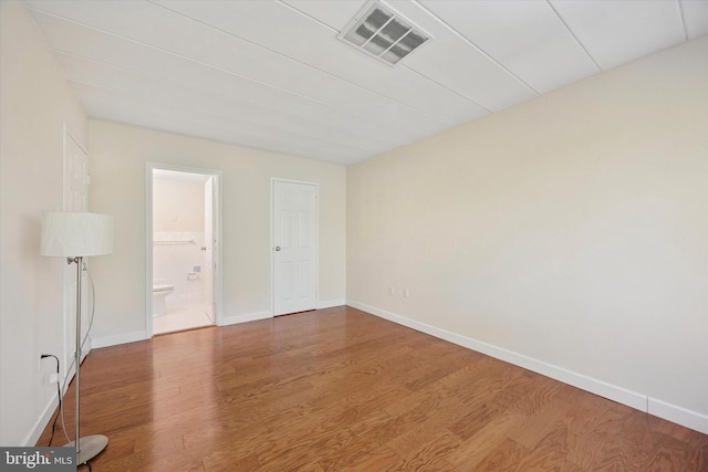empty room with baseboards, wood finished floors, and visible vents