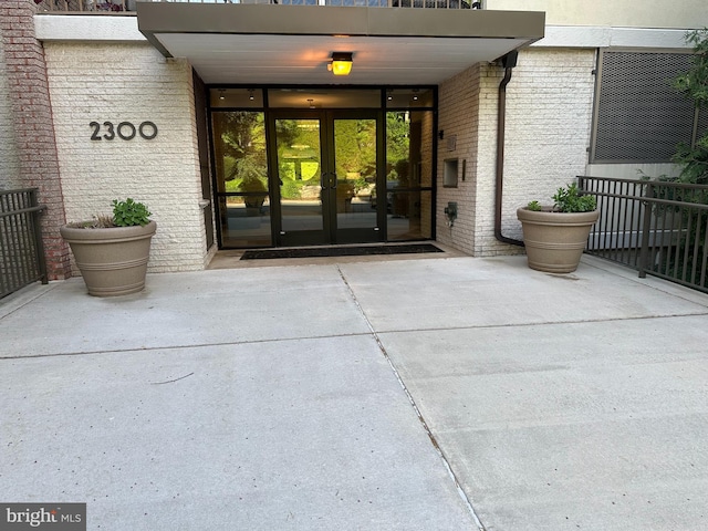 property entrance featuring brick siding, french doors, and a balcony