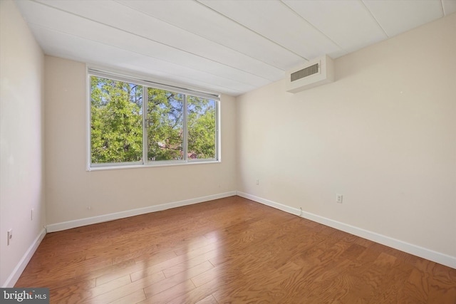 unfurnished room with baseboards, wood finished floors, and visible vents