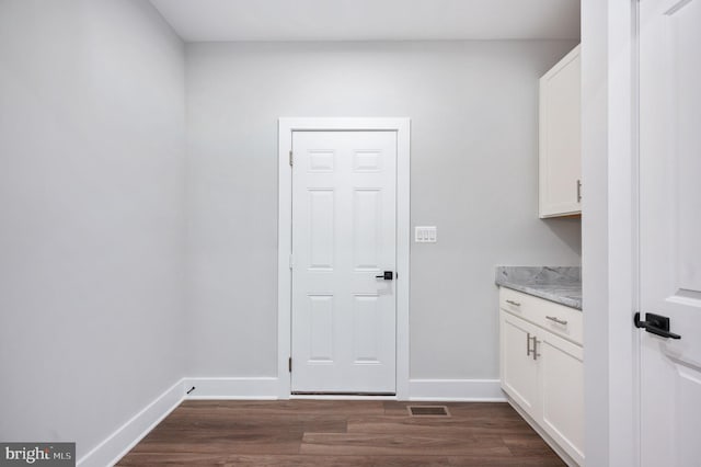 laundry area with visible vents, baseboards, and dark wood-style floors
