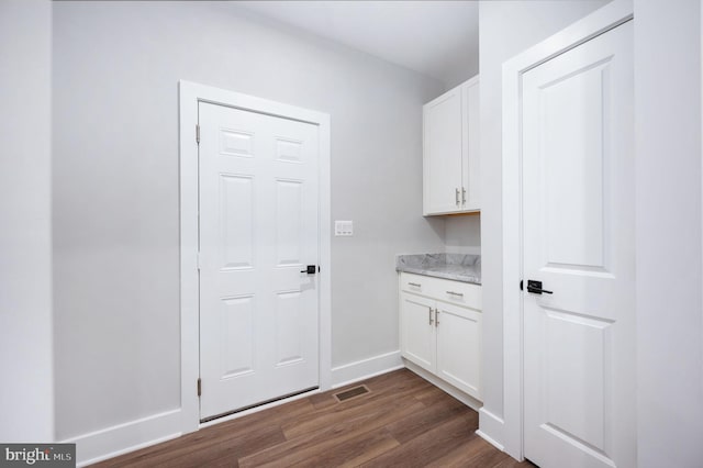 laundry area featuring baseboards, dark wood-style flooring, and visible vents