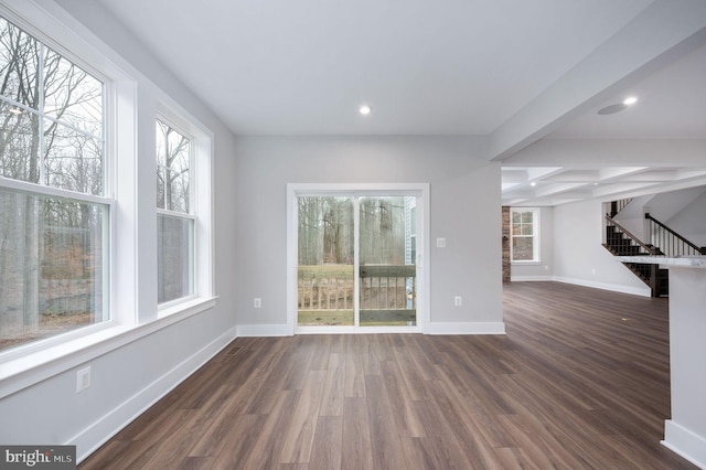 unfurnished living room with stairway, baseboards, plenty of natural light, and dark wood-style flooring