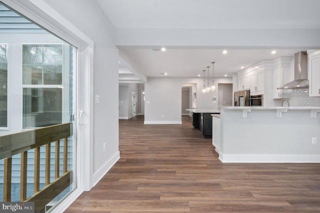 kitchen with dark wood-type flooring, light countertops, wall chimney exhaust hood, and appliances with stainless steel finishes